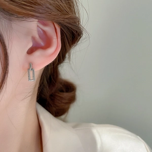 Close-up of minimalist silver rectangular geometric metal stud earrings worn by a model