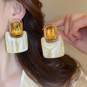 Close-up of vintage geometric earrings with amber stones and marble resin on model