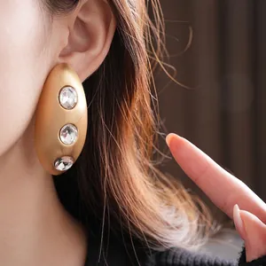 Brushed gold oval earrings with three clear crystals for a vintage luxury aesthetic
