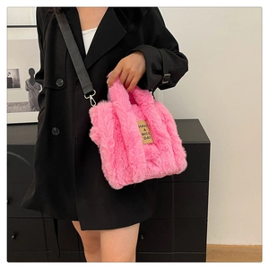 Pink plush tote bag with black detachable strap and Have a Nice Day patch detail