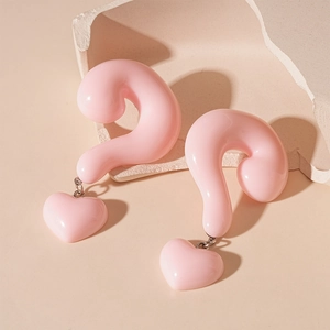 Detail of pink resin heart earrings featuring a unique 3D question mark design on stone