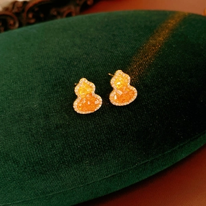 Détail de boucles d'oreilles gourde plaquées or 18K avec pierres orange sur velours