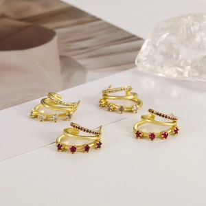 Close-up of gold layered C-shape earrings with inlaid pink and white zircon stones