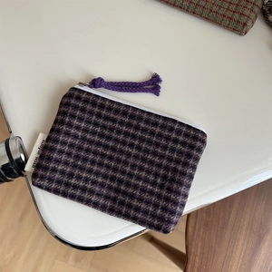 Detailed shot of tweed plaid pouch with a purple zipper pull and woven fabric texture