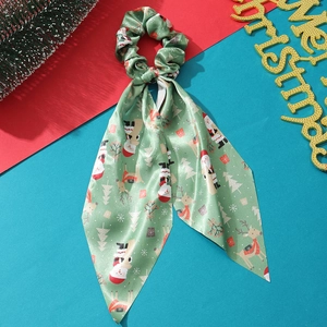 Detail of green Christmas scrunchie with long ribbons featuring festive satin patterns