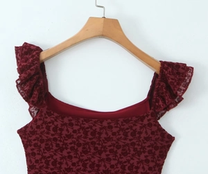 Detail of burgundy floral lace top with ruffled sleeveless design on a wooden hanger