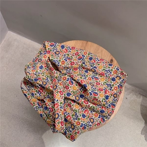Detail shot of vintage floral cotton tote bag on a wooden stool with a minimalist gray background