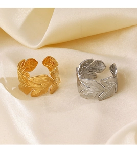 Detailed view of adjustable leaf rings in gold and silver finish on silk fabric