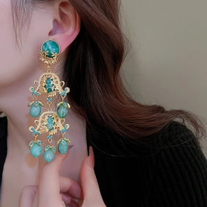 Détail des boucles d'oreilles baroques vintage avec résine verte et motif évidé doré