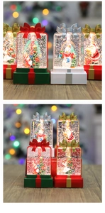 Close-up of lighted Christmas gift box lantern with Santa and glitter snow scene
