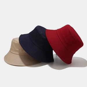 Detail of three cotton canvas bucket hats in beige, navy, and red with reinforced stitching