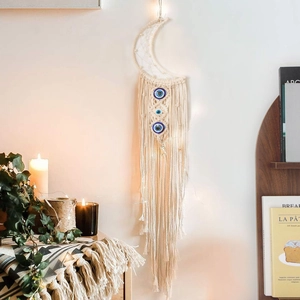 Detail of moon-shaped macrame wall hanging with blue evil eye beads and tassels