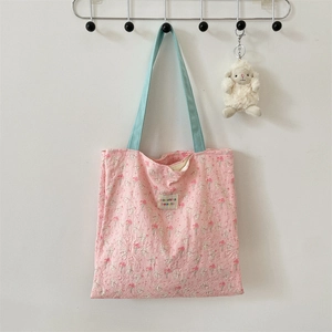 Detail of pink floral quilted tote bag with light blue straps and a cute sheep pendant