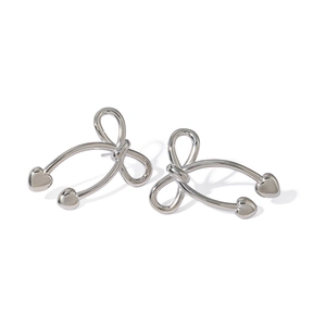 Detailed close-up of silver bow earrings with heart charms in polished stainless steel