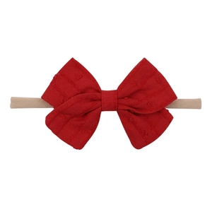 Macro detail of red bow baby headband showing soft textured fabric and elastic nylon band