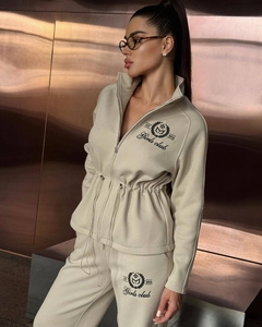 Close-up of beige knitted tracksuit with drawstring waist and Girls Club embroidery