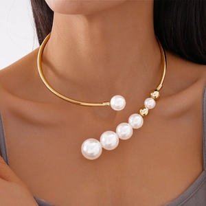 Close-up of a French vintage gold collar necklace with white faux pearls on a female model