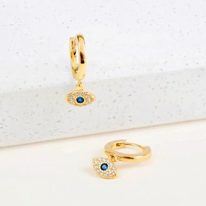 Détail de boucles d'oreilles œil maléfique dorées avec pierre bleue et zircons