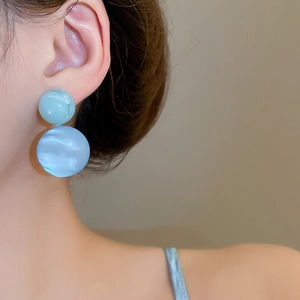Detailed close-up of light blue marble resin double ball earrings worn by model