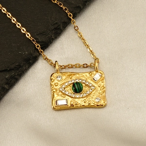 Macro detail of 18K gold-plated necklace featuring malachite and evil eye pendant detail