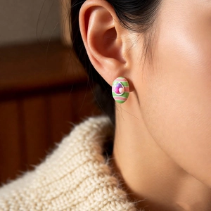 Macro view of pastel striped Easter egg stud earring worn by a model in soft light