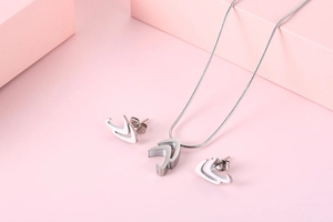 Detailed view of silver titanium steel necklace and stud earrings set on pink blocks