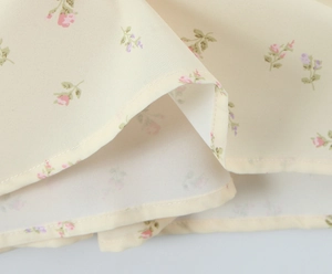 Detailed macro view of yellow floral chiffon fabric with delicate hem stitching quality