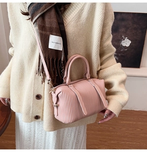 Detailansicht der rosa Faltenstruktur einer Boston-Handtasche mit goldener Hardware