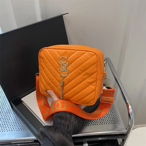 Orange quilted crossbody camera bag with gold CS logo, tassel and wide strap details