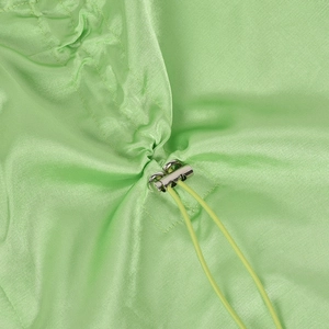 Detail of light green hollow pleated trousers with silver metal buckle and drawstring