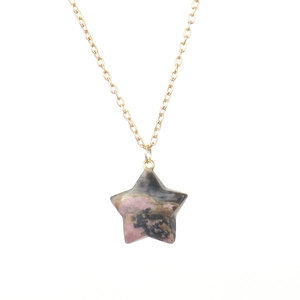 Macro detail of natural agate star pendant on a delicate gold chain necklace