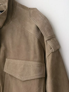 Détail des épaulettes et poches de poitrine sur veste en daim marron avec coutures fines