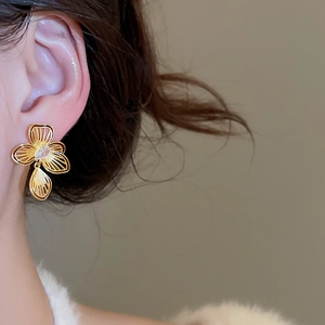 Close-up of gold-plated flower stud earring with zircon on ear of a fashion model