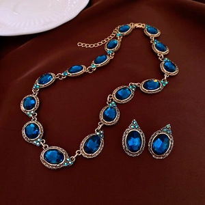 Détails du collier vintage doré et boucles d'oreilles gemme bleue sur velours brun