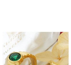 Nahaufnahme eines Vintage-Goldrings mit grünem Edelstein und strukturierten Details
