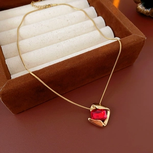 Macro shot of gold necklace with red square gemstone pendant in a brown jewelry box