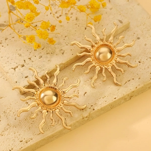 Exaggerated golden sun stud earrings on stone base with decorative dried flowers
