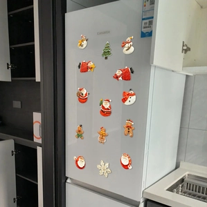 Detailed view of Christmas Santa and gingerbread man resin fridge magnets on white door