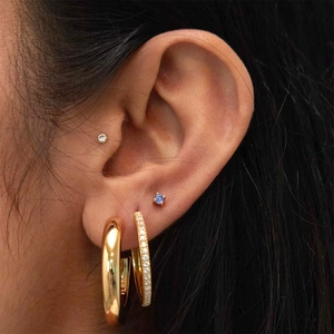 Détail de créoles en argent S925 et puces en zircon portées en style superposé