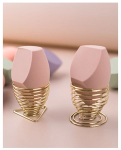 Detailed view of large pink makeup sponges in elegant golden spiral metal holders