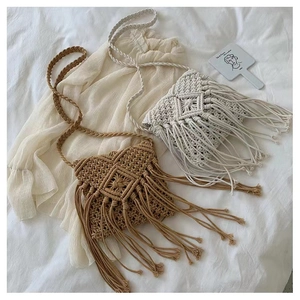 Detail of bohemian hand-woven straw crossbody bags with long tassels in khaki and cream white