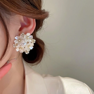 Detail view of a floral cluster earring with freshwater pearls on a model ear