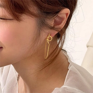 Detail of elegant gold knot earring with fine tassel chain worn by a female model