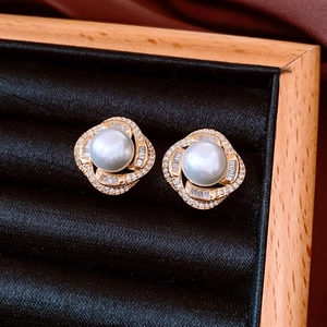 Macro shot of French style pearl stud earrings with zircon inlay on black velvet base