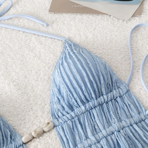 Detail of light blue pleated bikini top with marble bead and tie straps on plush rug