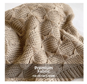 Close-up of beige knit fabric featuring 3D bow patterns and ribbed textured details