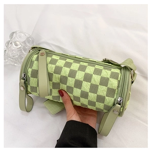 Close-up of green checkerboard cylinder bag with textured fabric and zipper detail