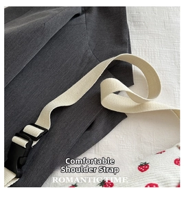 Detail of adjustable canvas strap and strawberry waffle pattern on a white crossbody bag