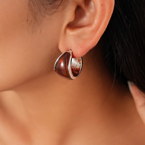 Close-up of amber resin C-shaped hoop earrings with silver edging on a model