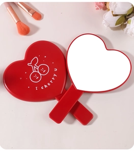 Dettaglio di uno specchio a mano rosso a forma di cuore con un design a ciliegia.
